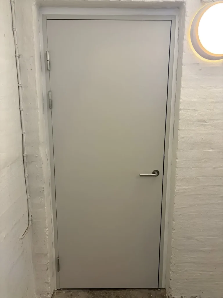Ny grå Swedoor BD60-branddør monteret i eksisterende muråbning i kælderen hos en ejerforening på Farum Hovedgade.